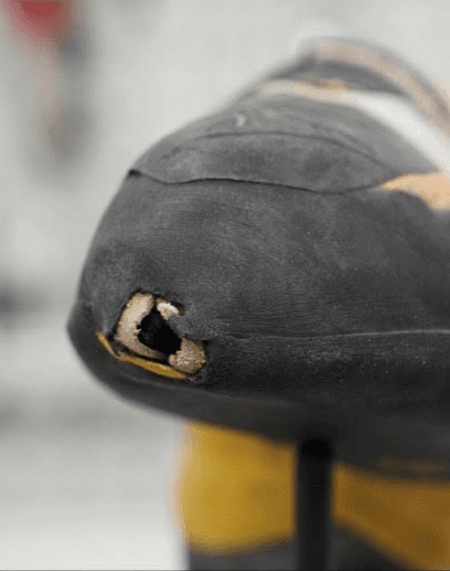Climbing shoe toe with a hole through the rubber